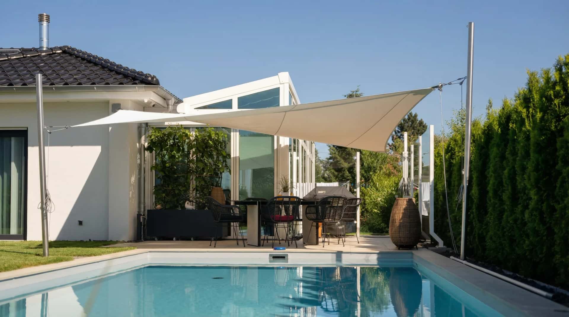 Sunfurl solsegel spännt vid pool med solstolar och grönska